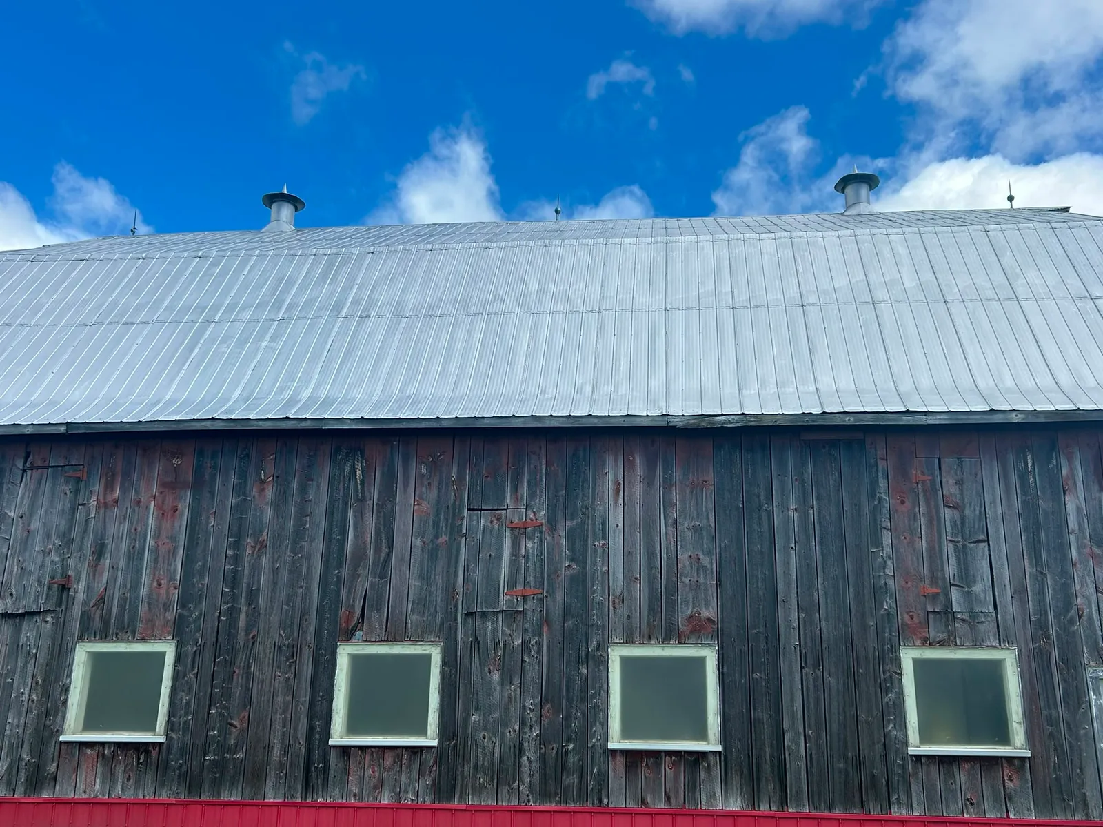 A barn roof part way through a fresh coat of metal roof paint by McIntosh Painting & Maintenance