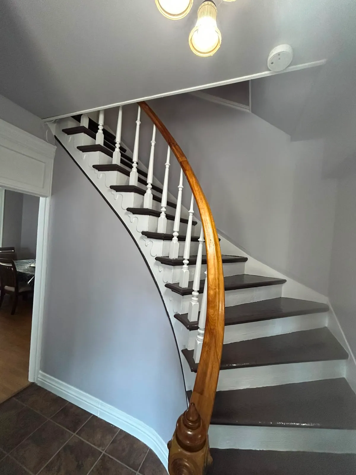 Restored curved staircase with white spindles and dark treads