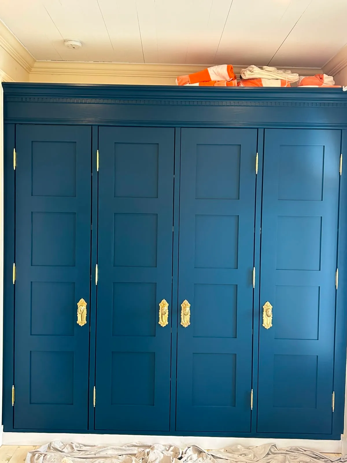 Deep-teal built-in wardrobe with gold hardware, freshly sprayed
